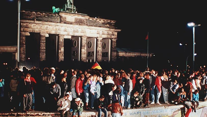 Die jüngste deutsche Revolution: Jubelnde Menschen stehen am 9. November 1989 auf der Berliner Mauer vor dem Brandenburger Tor.