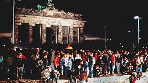 Die jüngste deutsche Revolution: Jubelnde Menschen stehen am 9. November 1989 auf der Berliner Mauer vor dem Brandenburger Tor.
