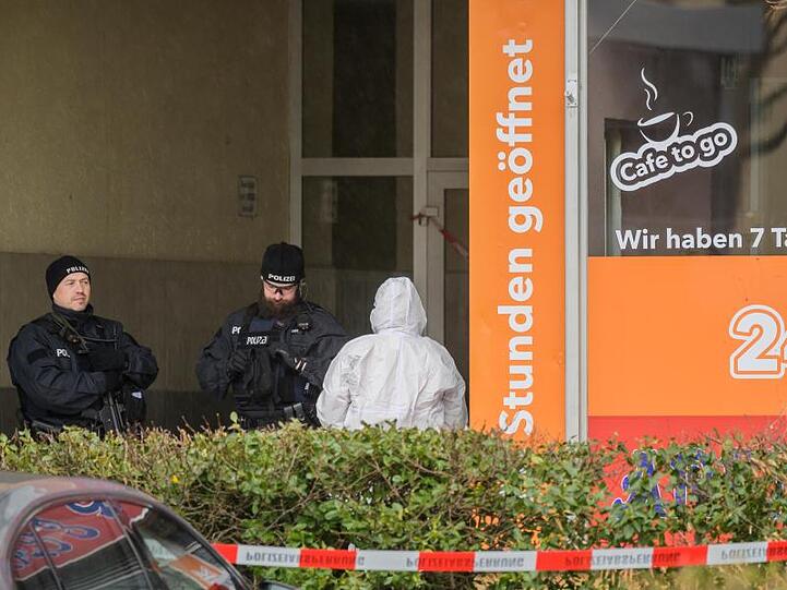 Zwei Polizisten und die Spurensicherung stehen am Tatort im Hanauer Stadtteil Kesselstadt.