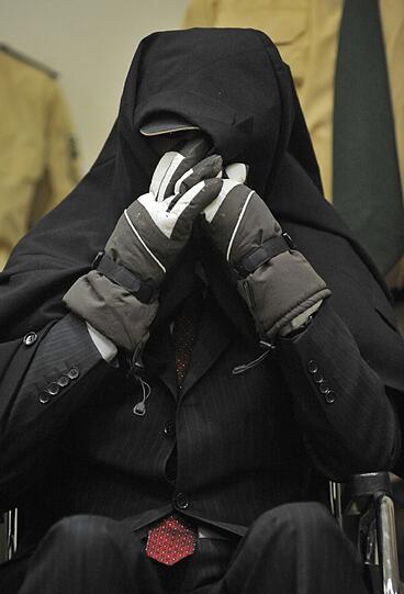 Der Angeklagte Wolfgang M. wird am Montag in den Verhandlungssaal im Landgericht in München gebracht und verbirgt dabei sein Gesicht hinter seinen Händen, die in Skihandschuhen stecken.