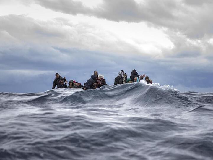 Männer aus Marokko und Bangladesch sitzen in einem überfüllten Holzboot im Mittelmeer vor der Küste von Libyen und warten auf die nahenden Retter der Organisation "Open Arms".