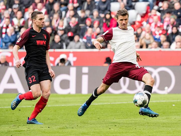Thomas Müller von München (r.) setzt sich im Zweikampf gegen Raphael Framberger von Augsburg durch. Foto: Matthias Balk/dpa