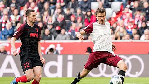 Thomas Müller von München (r.) setzt sich im Zweikampf gegen Raphael Framberger von Augsburg durch. Foto: Matthias Balk/dpa