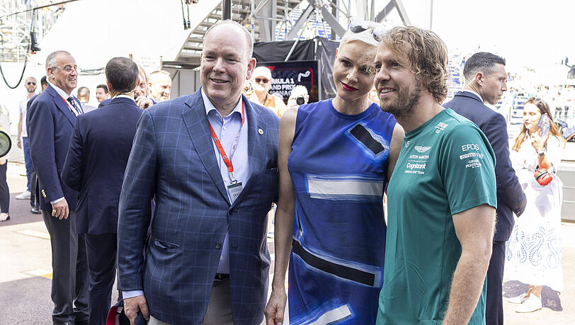 Schlendern durch die Boxengasse und treffen Sebastian Vettel (re.): Fürst Albert und Fürstin Charlene