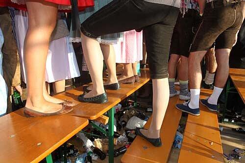 Feiernde Wiesnbesucher auf Bierbänken. Ein 23-Jähriger warf am Freitag eine Bierbank gegen einen Ordner.