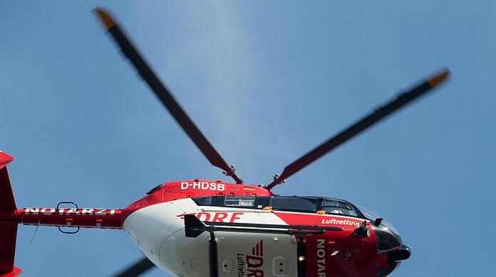 Ein Rettungshubschrauber fliegt über einem Klinikum.