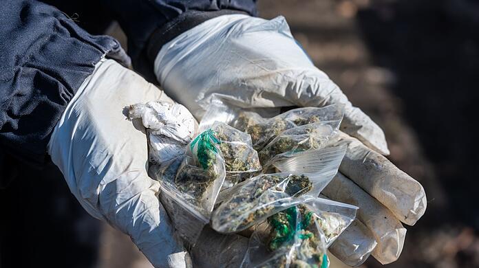 Eine Polizistin hält kleine Tütchen mit Marihuana in den Händen.