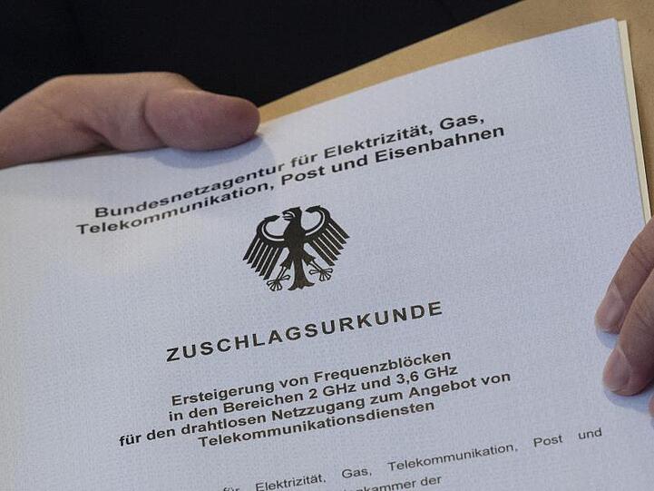 Die offizielle "Zuschlagsurkunde" wird dem Vertreter eines Mobilfunkunternehmens in den Räumen der Bundesnetzagentur übergeben.