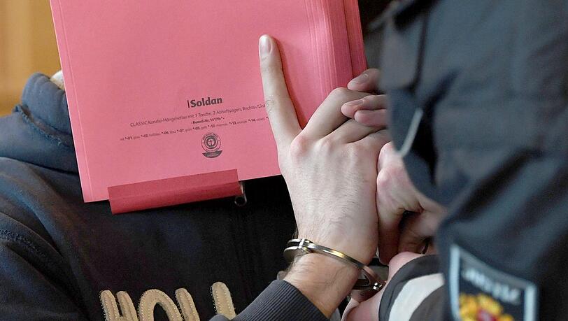 Ein Justizbeamter löst die Handschellen eines Angeklagten.