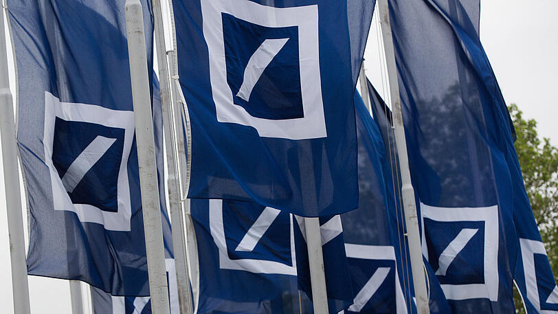 Fahnen mit dem Logo der Deutschen Bank wehen vor dem Eingang des Geldinstituts.
