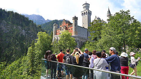 Touristen auf einer Aussichtsplattform unterhalb des Schlosses Neuschwanstein.