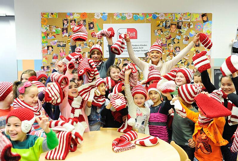 Fröhliche Bescherung: Schauspielerin Uschi Glas und Kirsten Bürgel (&bdquo;Kimoco&ldquo;, l.) verteilen die Mützen und Schals an die Grundschulkinder an der Paulckestraße.