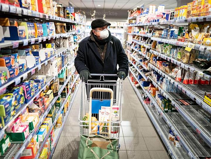 Ein Kunde kauft mit Mundschutz und Handschuhen in einem Supermarkt. Foto: Kay Nietfeld/dpa/Symbolbild