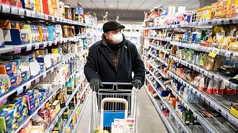 Ein Kunde kauft mit Mundschutz und Handschuhen in einem Supermarkt. Foto: Kay Nietfeld/dpa/Symbolbild