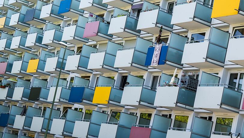 Die Balkone an der Fassade eines Wohnhauses in München sind teilweise bunt verkleidet. Kommunen prangern große Probleme beim Wohnungsbau an.