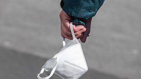 Ein Passant trägt eine FFP2-Maske in der Hand.