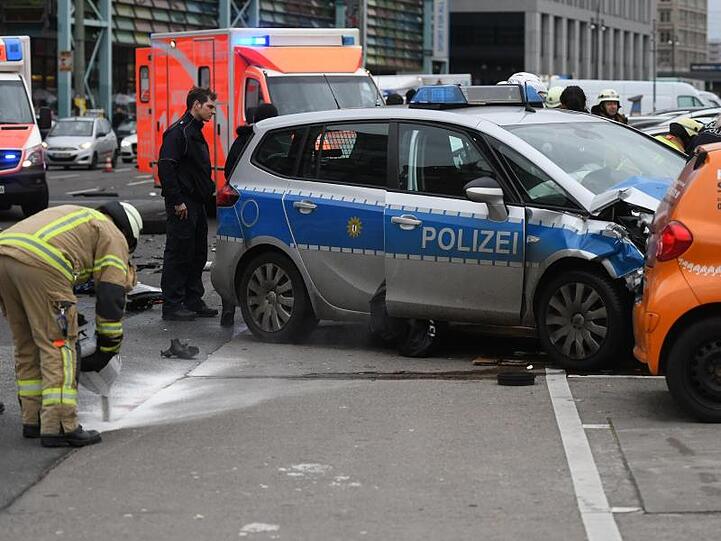 Ein Polizist und Feuerwehrmänner am Unfallort in Berlin.