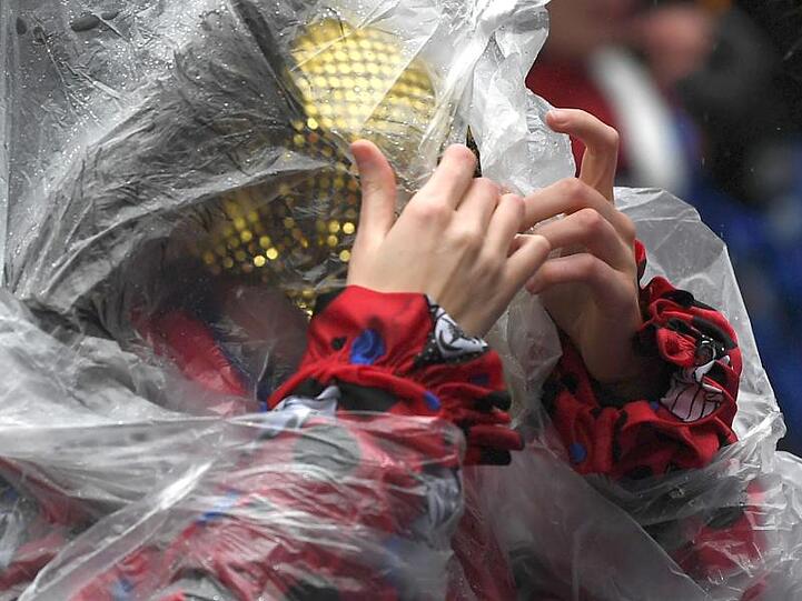 Eine Karnevalistin schützt sich in Köln mit einem Regenponcho gegen das stürmische Wetter.