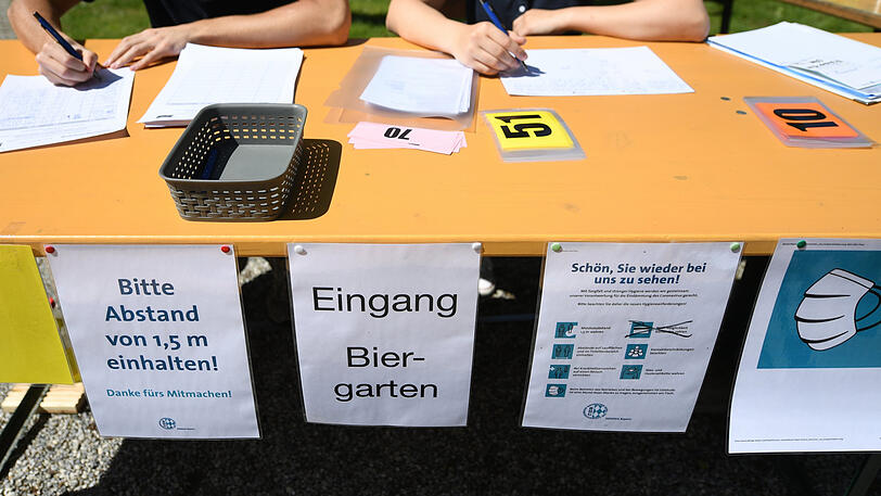 Zwei Mitarbeiter eines Biergartens notieren sich alle Gäste.