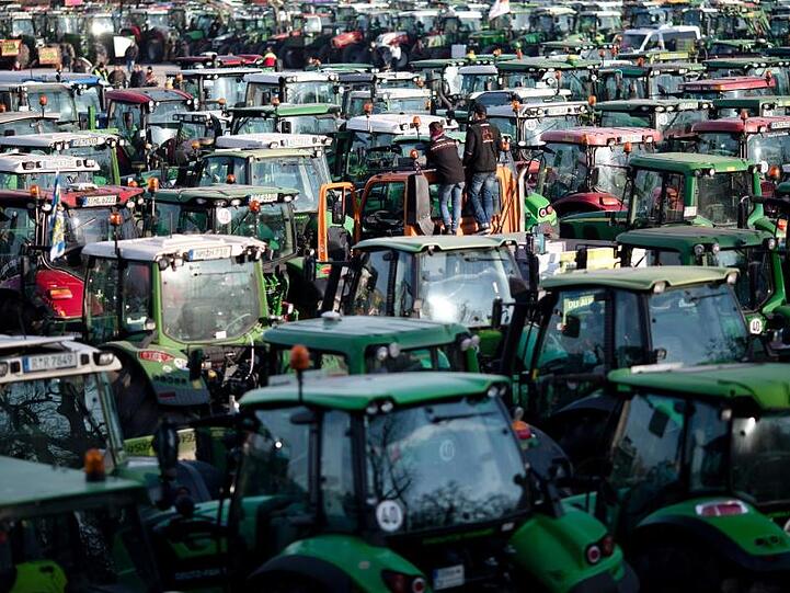 Zwei Landwirte verfolgen auf einem Traktor die Großdemonstration. Foto: Daniel Karmann/dpa/Archivbild