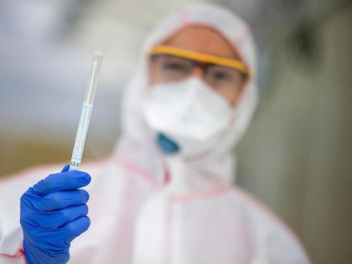 Ein Mitarbeiter hält in einem Abstrichzentrum einen Coronatest-Abstrich in der Hand. Foto: Sebastian Gollnow/dpa/Symbolbild