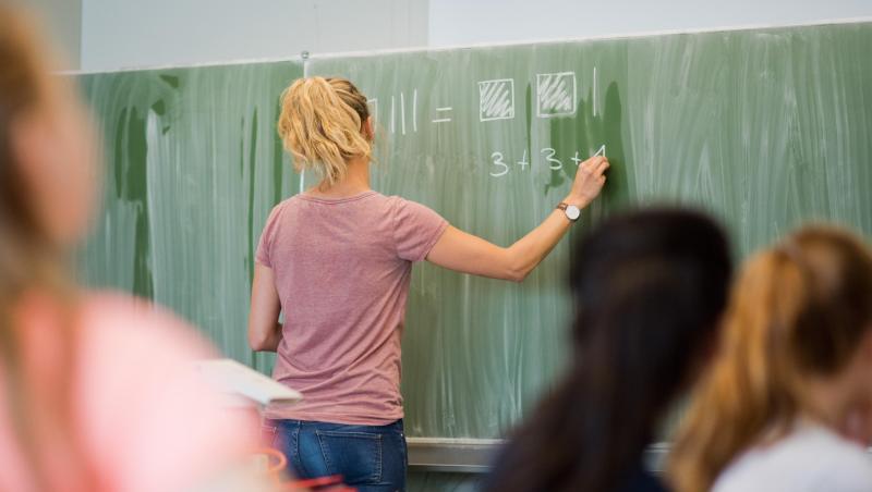 Eine junge Lehrerin schreibt an eine Schultafel. Foto: Julian Stratenschulte/Archivbild Eine junge Lehrerin schreibt an eine Schultafel. Foto: Julian Stratenschulte/Archivbild
