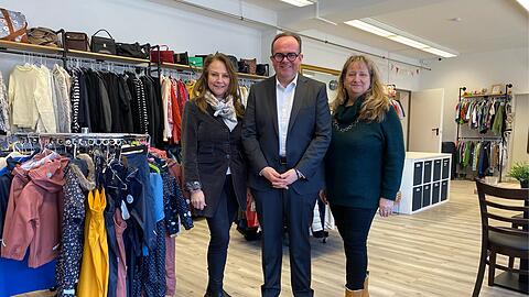 OB-Kandidat Clemens Baumg&auml;rtner (CSU) vor viel Secondhand-Klamotten im neuen Nachbarschaftstreff  "Giesinger Herz" &ndash; zwischen den CSU-Stadtr&auml;tinnen Ulrike Grimm (l.) und Alexandra Ga&szlig;mann.