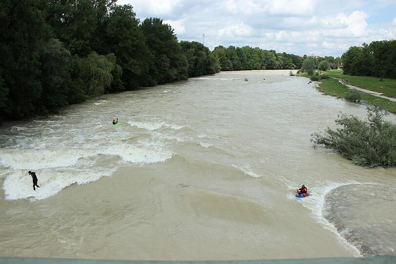 Hochwasser für die einen, perfekte Wellen für die anderen. Waghalsig tummeln sich Sportler in der Isar.