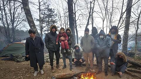 Migranten versammeln sich an der belarussisch-polnischen Grenze an einem Feuer, um sich zu wärmen.