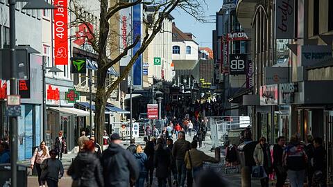 Passanten gehen bei Sonnenschein durch eine Einkaufsstraße in einer Fußgängerzone. Foto: Gregor Fischer/dpa/Symbolbild