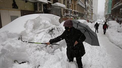Eine Frau befreit ihr Auto in Madrid vom Schnee.