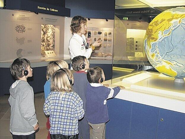 Eine Museumspädagogin erklärt die Welt: Über Kopfhörer erfahren die Kinder in einer Führung alles über den &bdquo;Unruhigen Planet Erde&ldquo;.