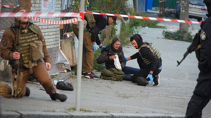Sanitäter helfen einer verletzten Frau nach dem Beschuss von Gebäuden in Kiew durch eine Drohne.