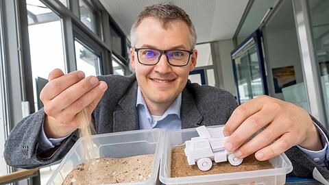 Luitpold Fried vom Start-Up-Unternehmen „Bind-X“ zeigt an einem Beispiel, wie mit einem speziellen Bindemittel aus ungefestigtem Sand, eine feste Verbindung entstehen kann, die zur Reduzierung von Staub auf unbefestigten Straßen führt.