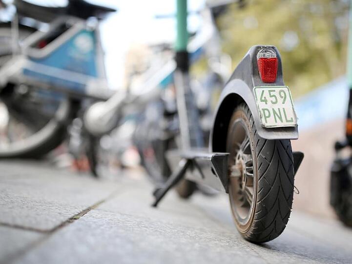 E-Scooter stehen vor Leihfahrrädern. Foto: Martin Gerten/dpa