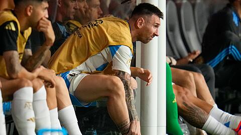 Lionel Messi fasst sich an den geschwollenen verletzten rechten Knöchel.