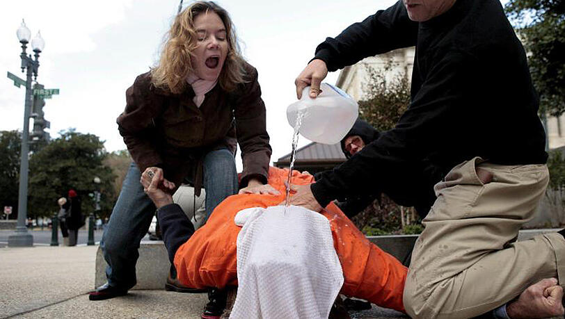 Menschenrechtsaktivisten demonstrieren Waterboarding an einem Freiwilligen. Menschenrechtsaktivisten demonstrieren Waterboarding an einem Freiwilligen.
