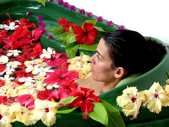Ayurveda-Urlaub: Frau entspannt in einem Bad aus Blüten