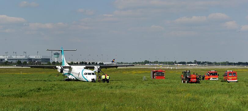 Mitarbeiter des Flughafens in München betrachten die Maschine der italienischen Fluggesellschaft, die am Donnerstag auf dem Münchner Flughafen notlanden musste. Das Flugzeug mit 62 Menschen an Bord hatte kurz nach dem Start in Richtung Venedig umdrehen müssen, weil sich Rauch in der Kabine entwickelt hatte. Bei der Landung wurden fünf Personen leicht verletzt, die Maschine kam neben der Landebahn zum Stehen.