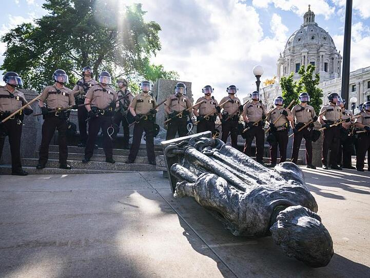 Polizisten umzingeln die Statue von Christopher Columbus, nachdem diese vor dem "Minnesota State Capitol" von ihrem Sockel gestürzt worden ist.