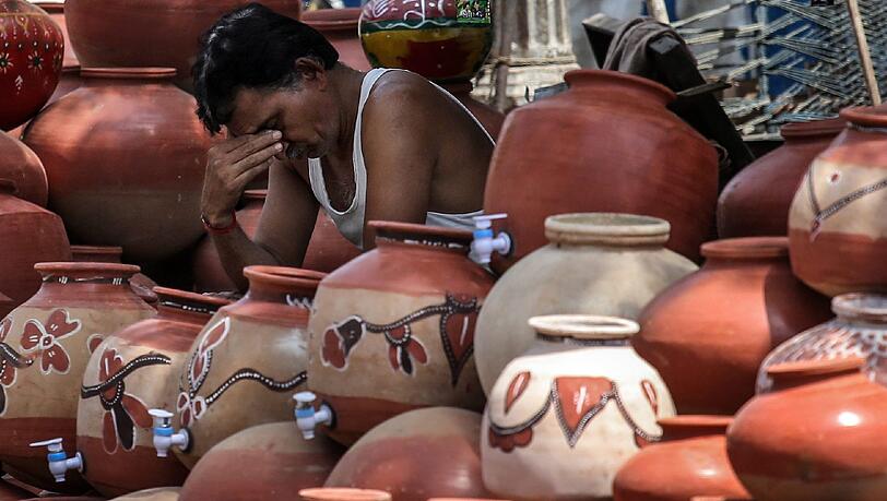 Ein Mann sackt erschöpft in sich zusammen: Eine Hitzwelle setzt den Menschen in Indien zu. Ein Mann sackt erschöpft in sich zusammen: Eine Hitzwelle setzt den Menschen in Indien zu.