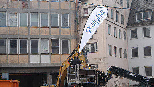 Alles bereit für den Fototermin: Der Abrissbagger mit dem Furcht einflößenden Greifer und die Fahnen von Gerd Schmelzers „alpha“-Immobilien-Gruppe. Alles bereit für den Fototermin: Der Abrissbagger mit dem Furcht einflößenden Greifer und die Fahnen von Gerd Schmelzers „alpha“-Immobilien-Gruppe.