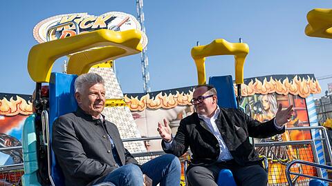 Oberbürgermeister und Festleiter testen vor dem Start ein Fahrgeschäft.
