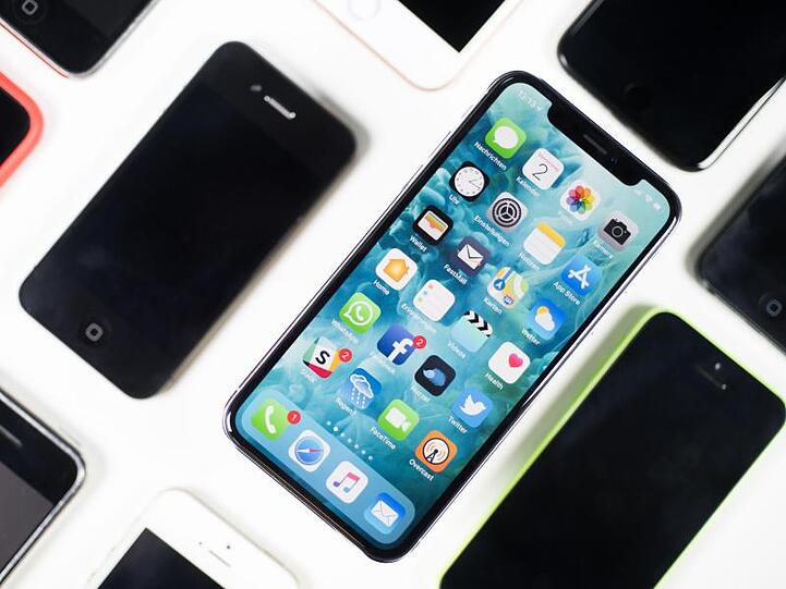 Ein iPhone X liegt neben iPhones anderer Generationen auf einem Tisch.