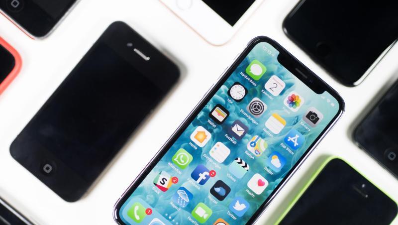 Ein iPhone X liegt neben iPhones anderer Generationen auf einem Tisch. Ein iPhone X liegt neben iPhones anderer Generationen auf einem Tisch.