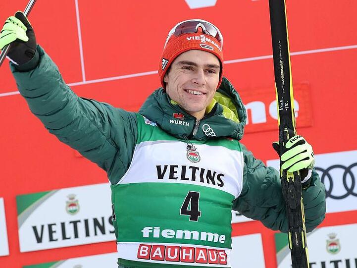 Der erstplatzierte Vinzenz Geiger jubelt auf dem Podium über seinen Sieg beim Weltcup in Val di Fiemme.