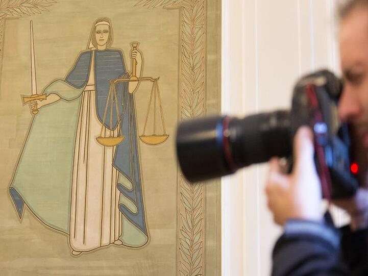 Ein Fotograf vor dem Bild der Justitia. Foto: Friso Gentsch/dpa/Archivbild