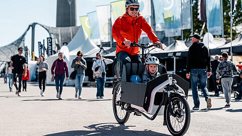 Ein junger Mann dreht bei den E-Bike-Days vergangenes Jahr mit seinem Kind eine Runde auf einem E-Lastenrad. Die liegen vor allem bei Familien im Trend. In München sieht man immer mehr junge Eltern mit ihren Kindern auf E-Lastenrädern.