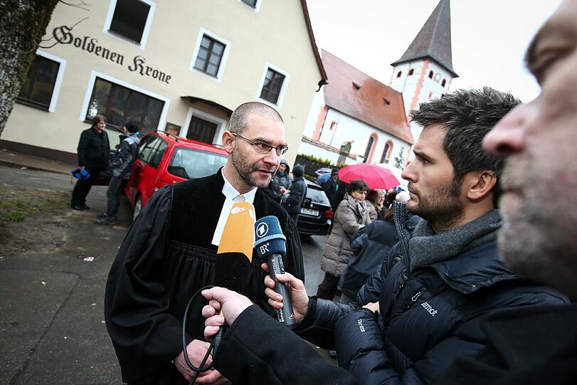 Pfarrer Björn Schukat spricht nach einer Menschenkette um einen durch einen Brandanschlag zerstörten, ehemaligen Gasthof in Vorra mit Medienvertretern.