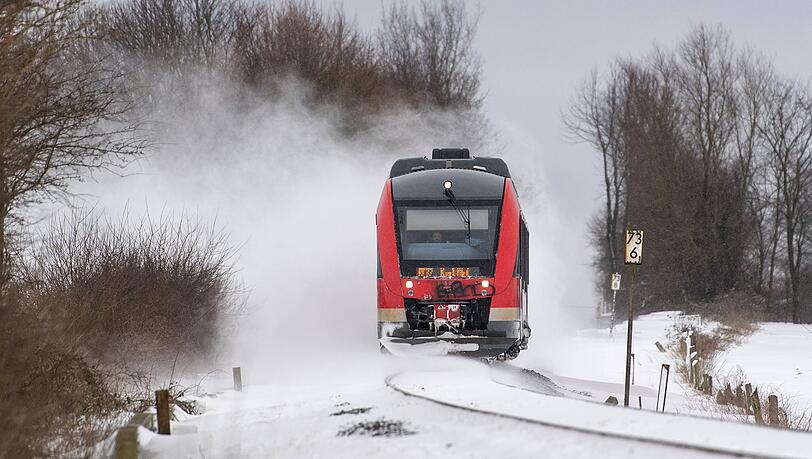 Eine Regionalbahn fährt über zugeschneite Gleise. Eine Regionalbahn fährt über zugeschneite Gleise.